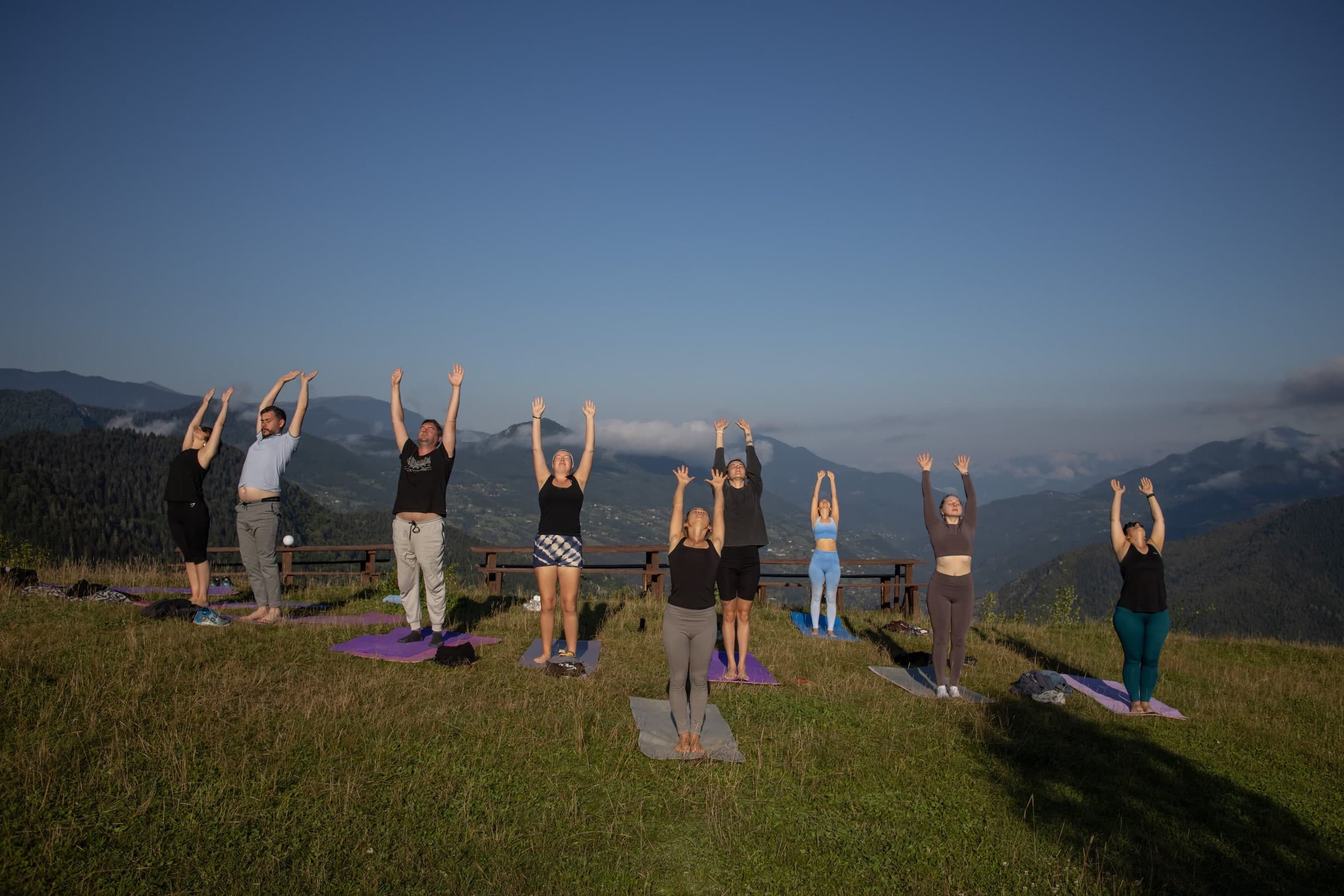 Group of people doing yoga outdoors on a mountain retreat, Glamping Tago, Georgia.