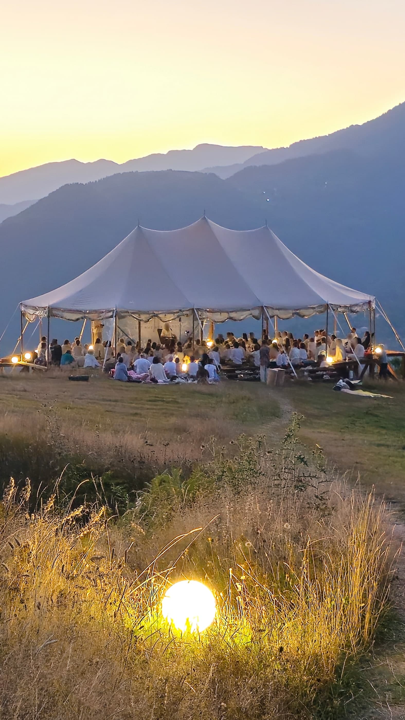 Large meditation retreat in a white tent, glowing orb, mountains at sunset, Glamping Tago, Georgia.